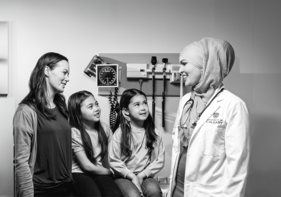 A doctor, two children, and a woman are in conversation with each other.