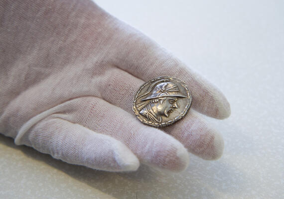 A white-gloved hand holding an ancient coin