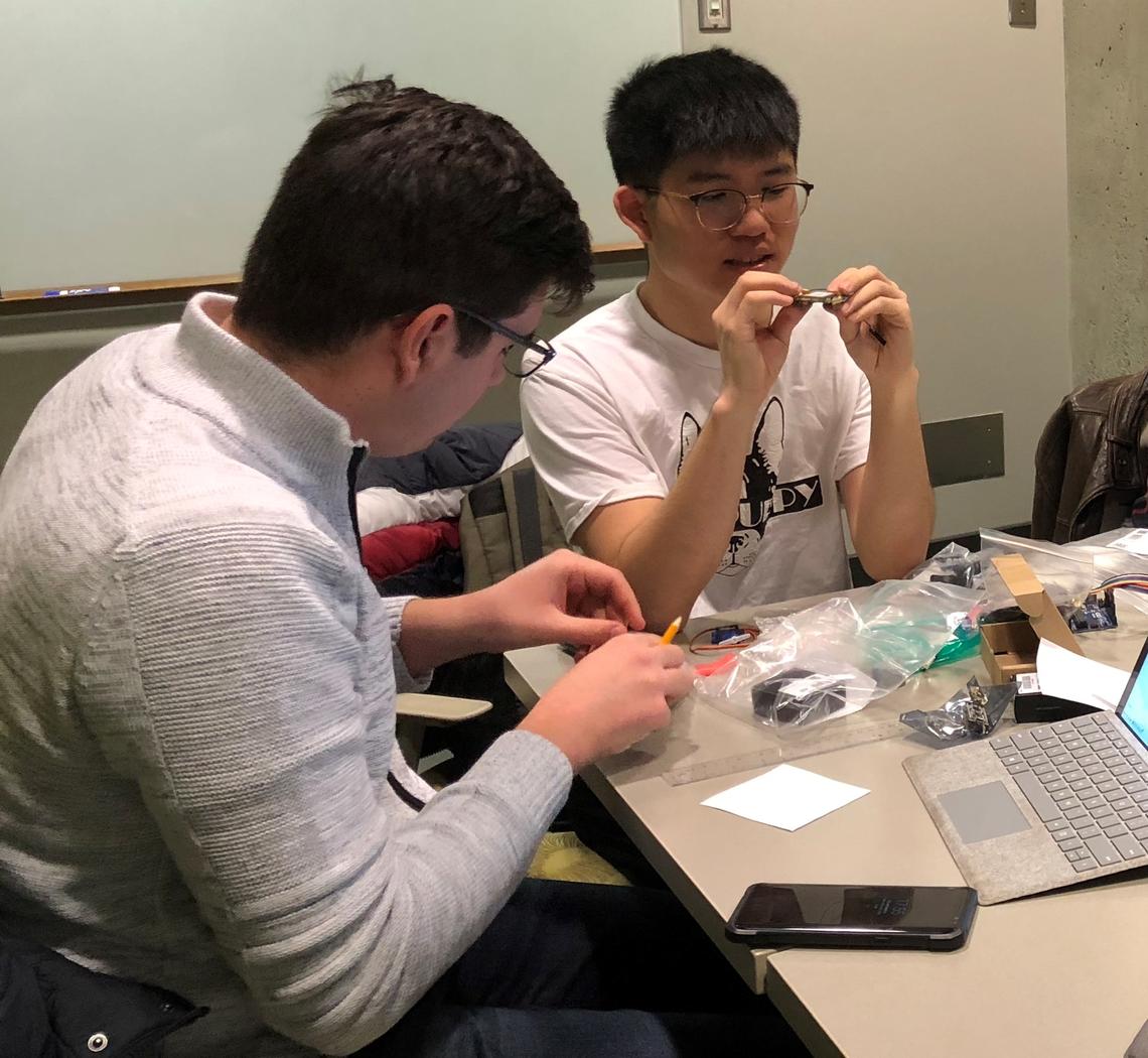 University of Calgary students Sabin Nastase and Douglas Liao examine some of the electrical components they will use to build a prototype device.