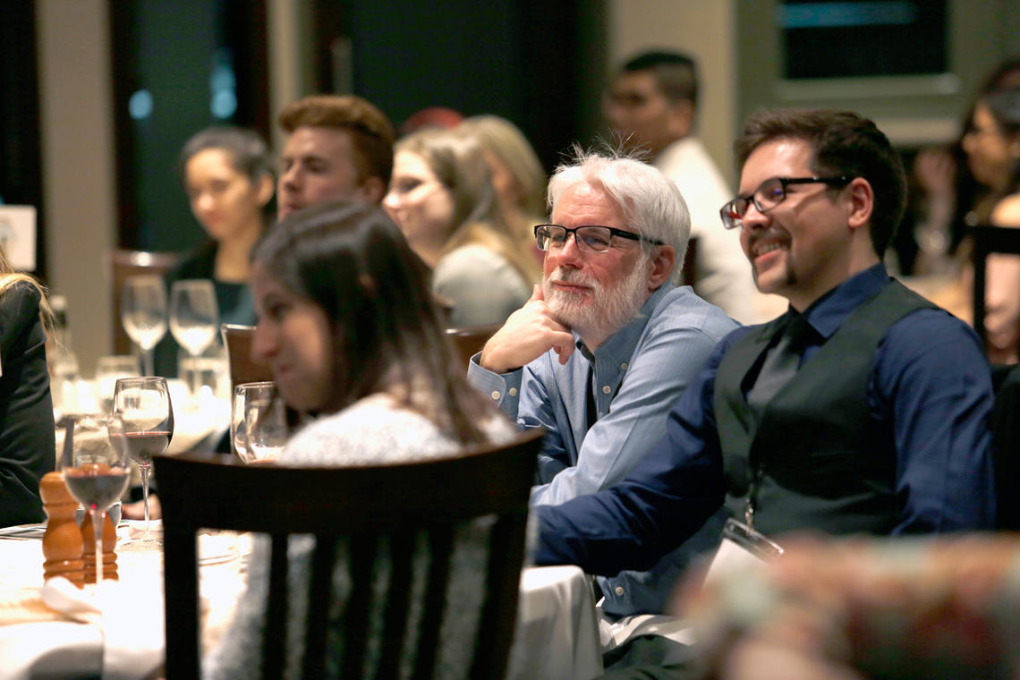 Jordan Bartsch, far right, enjoys the keynote presentation at Industry Night 2019, an event hosted at the Silver Springs Golf and Country Club by the Society of Undergraduates in Economics (SUE) 