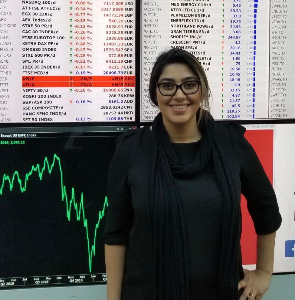 Atena in front of stock tracking board in the Haskayne School of Business