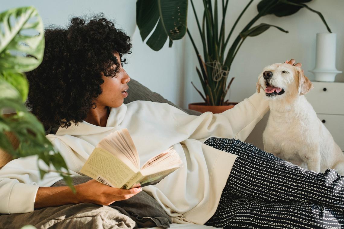 Woman pets her dog while reading a book