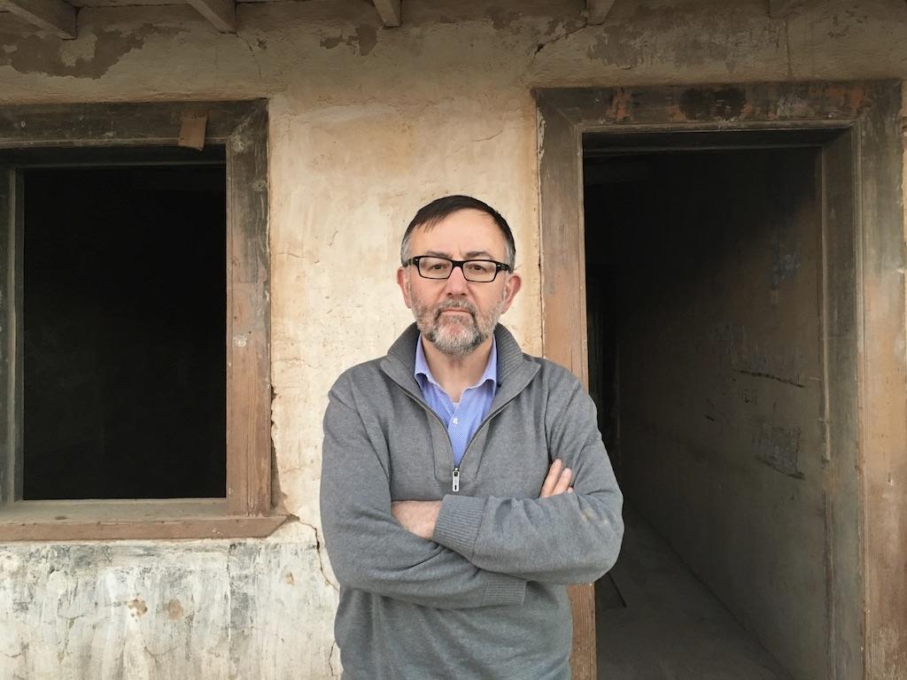 Policzer standing in front of abandoned mining camp