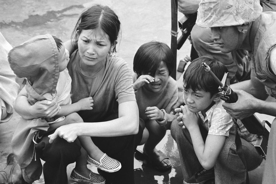 A weeping South Vietnamese mother and her three children on the deck of an amphibious command ship are rescued from Saigon by U.S. Marine helicopters in Vietnam in April 1975.
