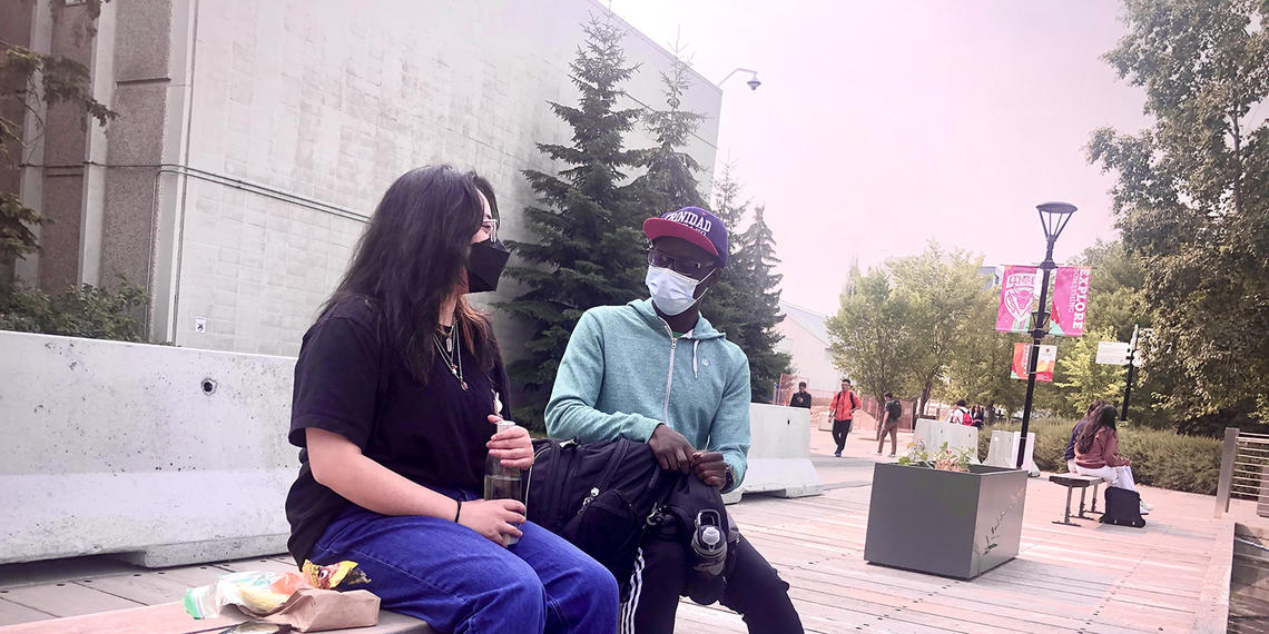 students wearing masks sitting on a bench