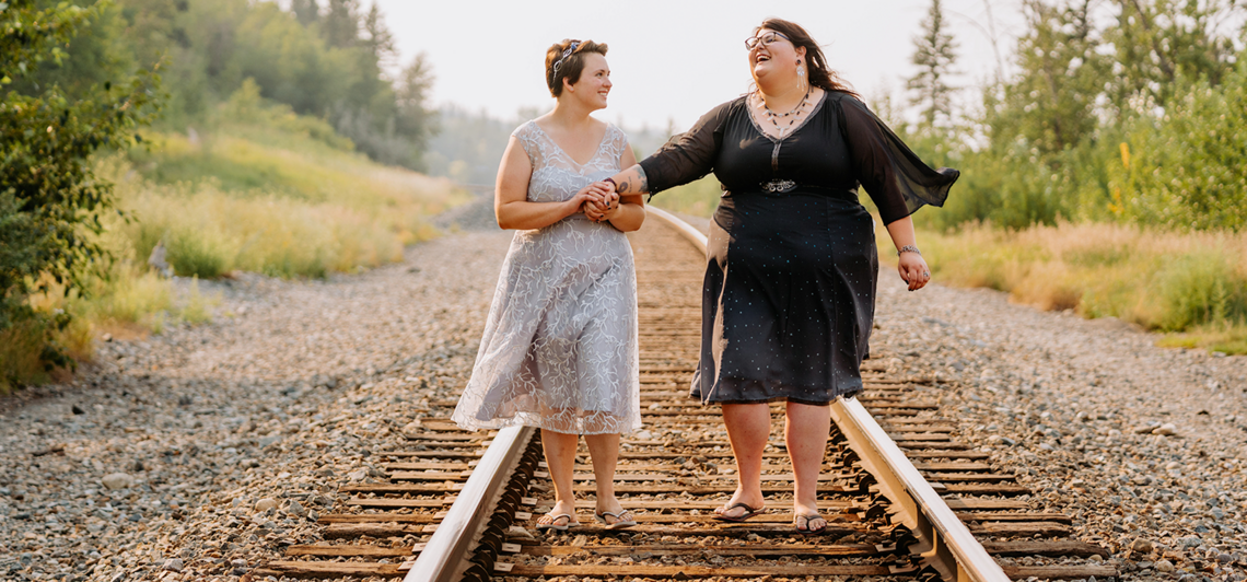 Katie Delucia Burk and her wife Emily walk on train tracks