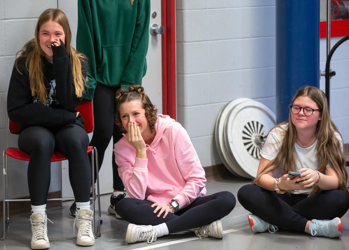 A group of young girls sitting on the floor watching something off camera