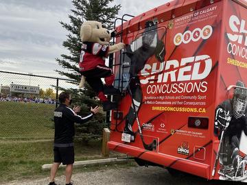 Gordie the Bantam Football mascot climbs up the back of the SHRed mobile