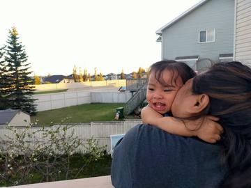 Child clings to its mother in a Calgary backyard