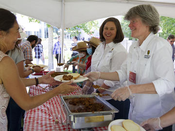 UCalgary Registrar Amy Dambrowitz (middle) and Provost Teri Balser (right) serve beef on a bun to community members during the President's Stampede BBQ on July 12. 