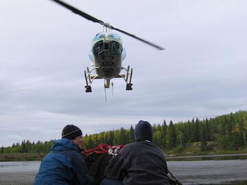 A shot of three peoples backs looking up at a helicopter