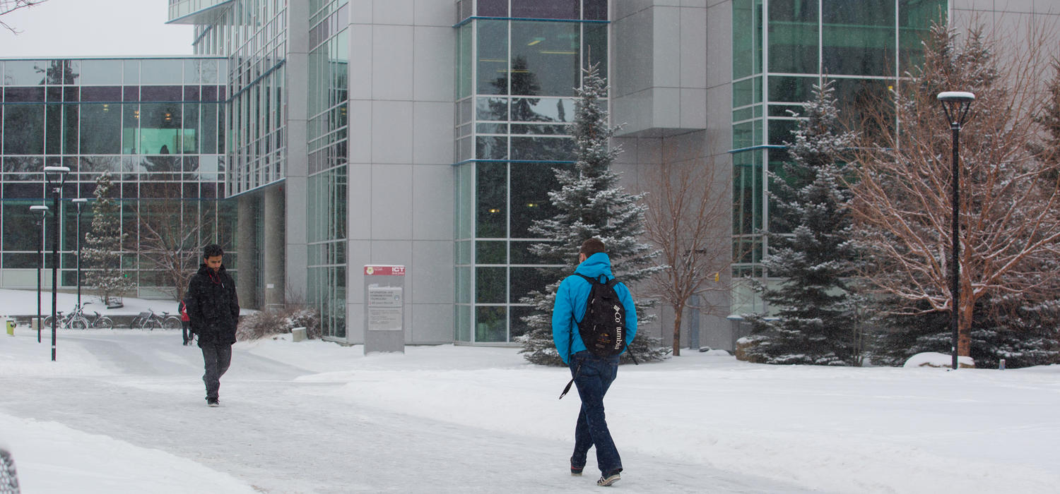Two people walk in the snow on main campus