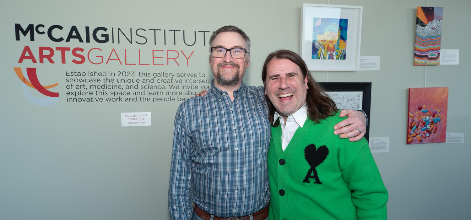 Two men stand in front of a mccaig institute sign