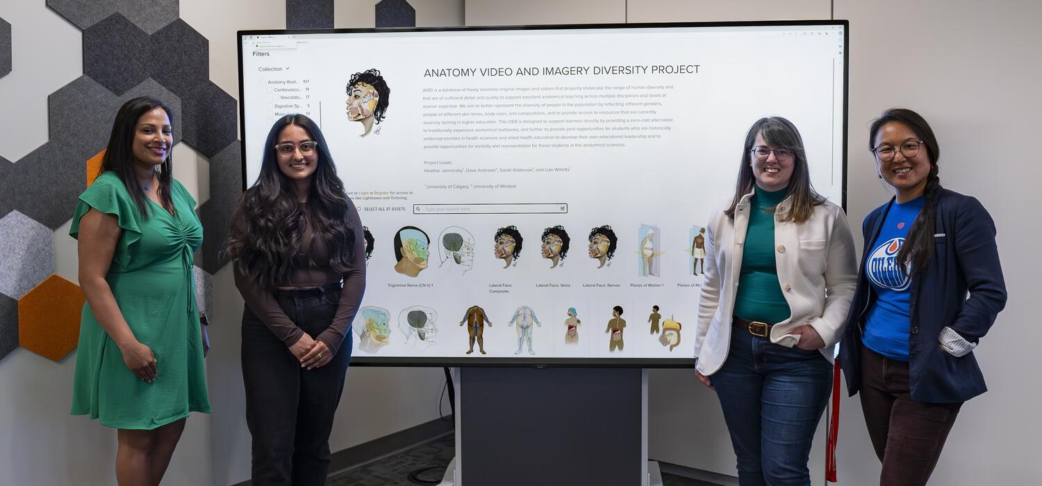Four women stand around a presentation board