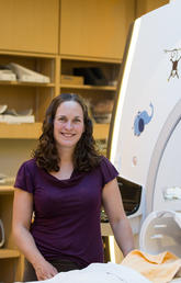 Dr. Catherine Lebel standing in front of a MRI at the Alberta Children's Hospital