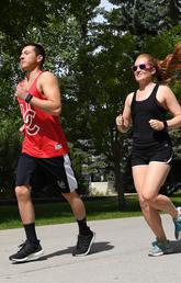 Two people wearing smart watches and running on UofC campus