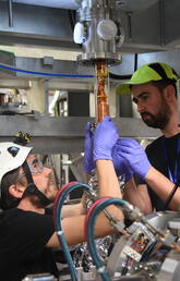 Timothy Friesen and UCalgary PhD student Adam Powell install a charged particle trap for making antihydrogen atoms into the ALPHA-g apparatus at CERN. 