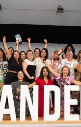 Co-authors of Landed: Transformative Stories of Canadian Immigrant Women celebrate book launch in front of Landed sign.