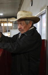 Man stands in a barn wearing a cowboy hat