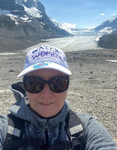 A woman takes a selfie in front of a glacier 