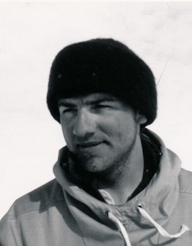 A black and white photo of a man wearing a winter coat and winter hat