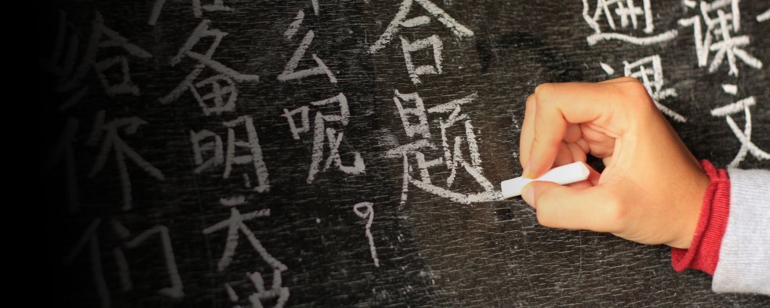 Stock image of a person's hand writing in Chinese on a blackboard