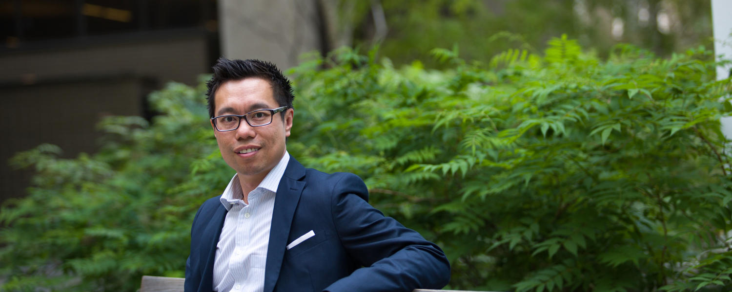 Andrew Szeto, sitting outside on a bench, was named Mental Health Director at the University of Calgary in 2016.