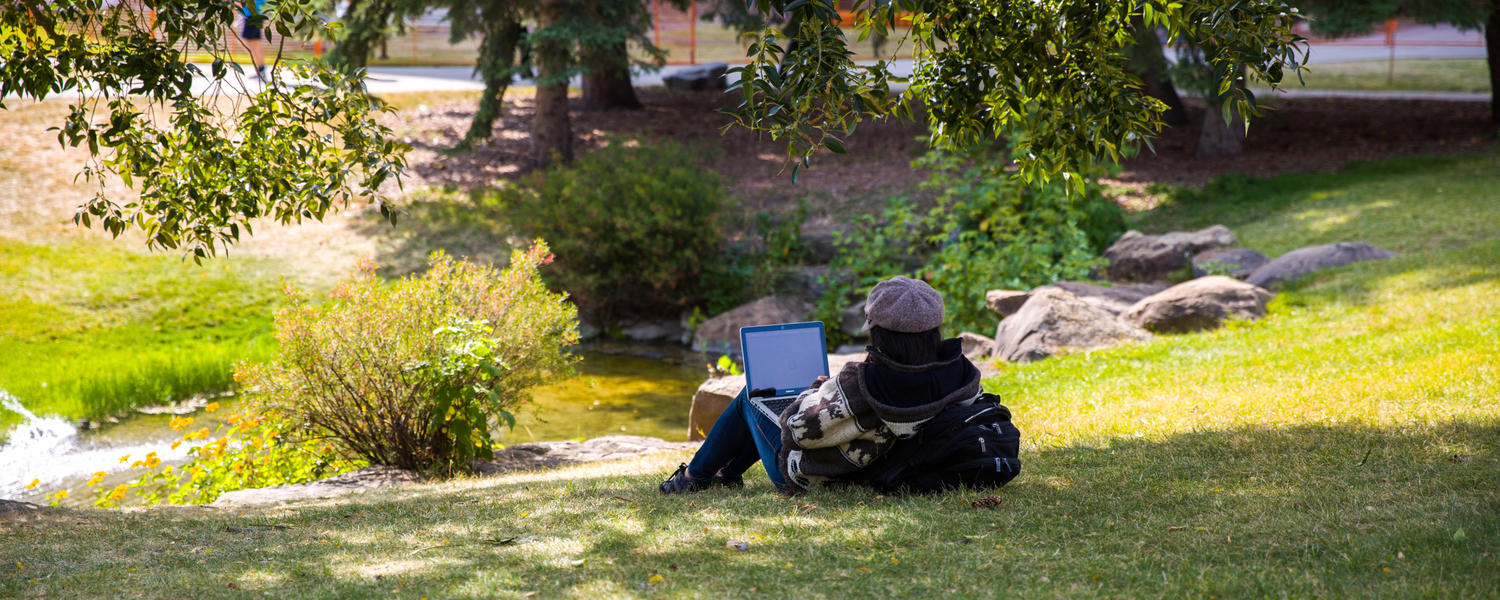 Students lie on the grass on campus in the summer