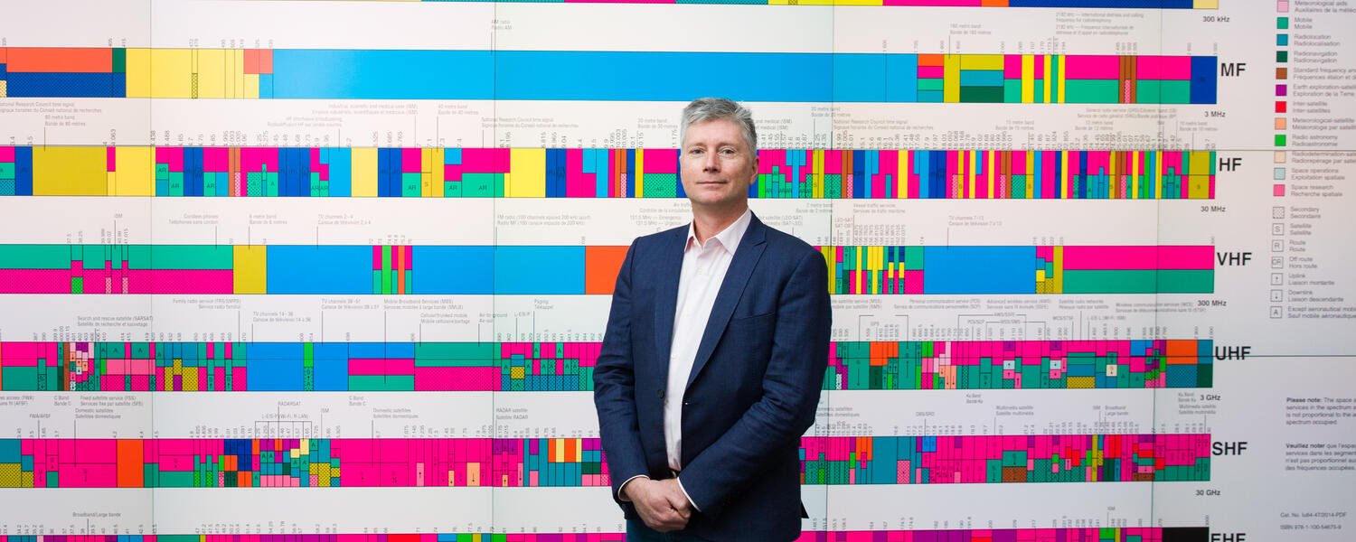 Professor Teylor standing in front of a large colorful graphics wall 