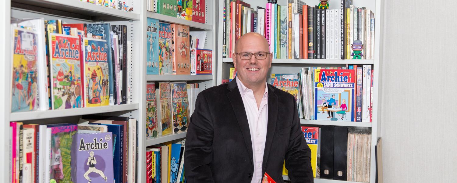 Bart Beaty sitting in front of book shelves 