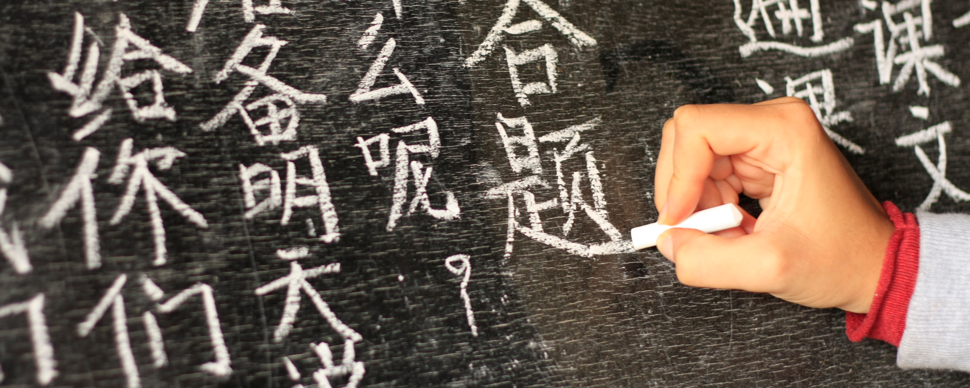 Girl writing Chinese characters on a blackboard at a remote school in Northern Thailand. - stock photo