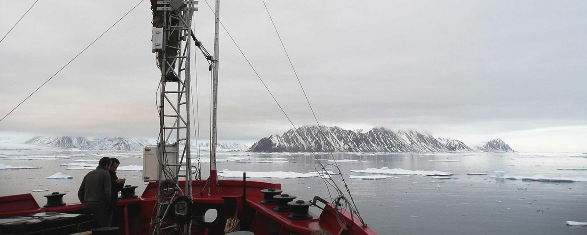 Arctic researchers on a boat with equipment and a glacier in the background