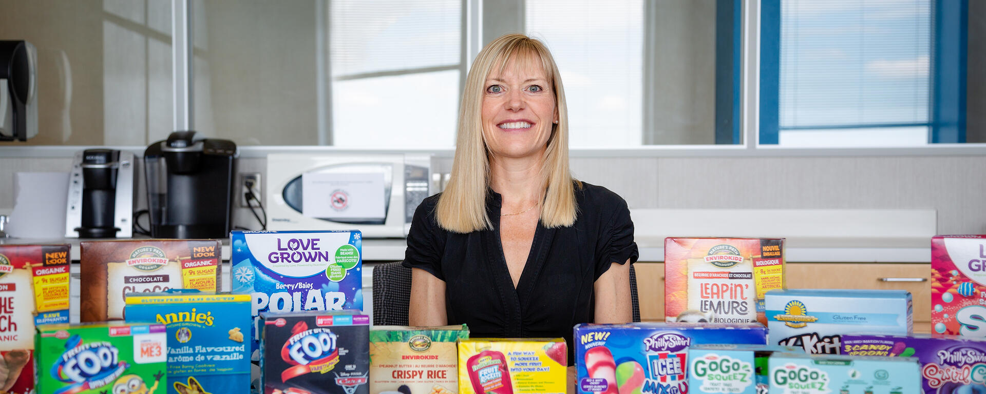 Charlene Elliott sits with boxes of sugary children's cereal and snacks