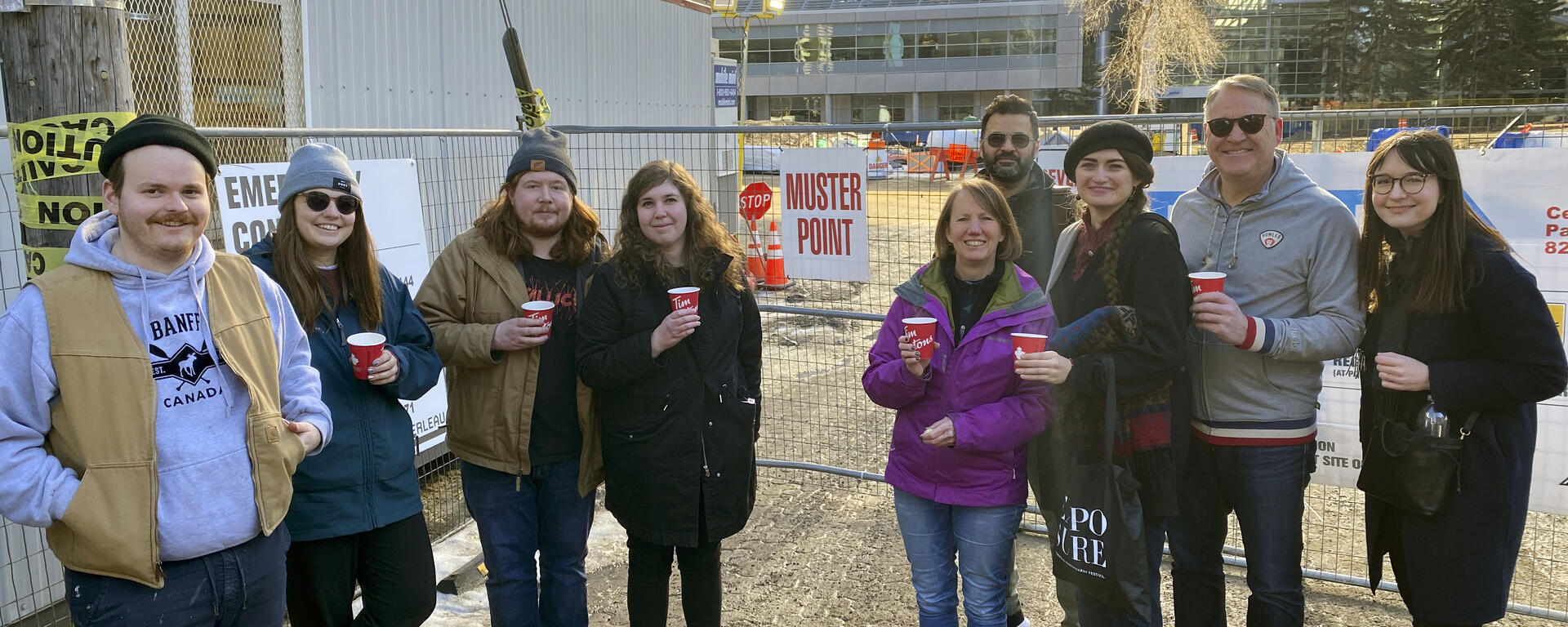 Crew of researchers on site for Exposure festival. They all hold Tim Horton's cups and smile at the camera
