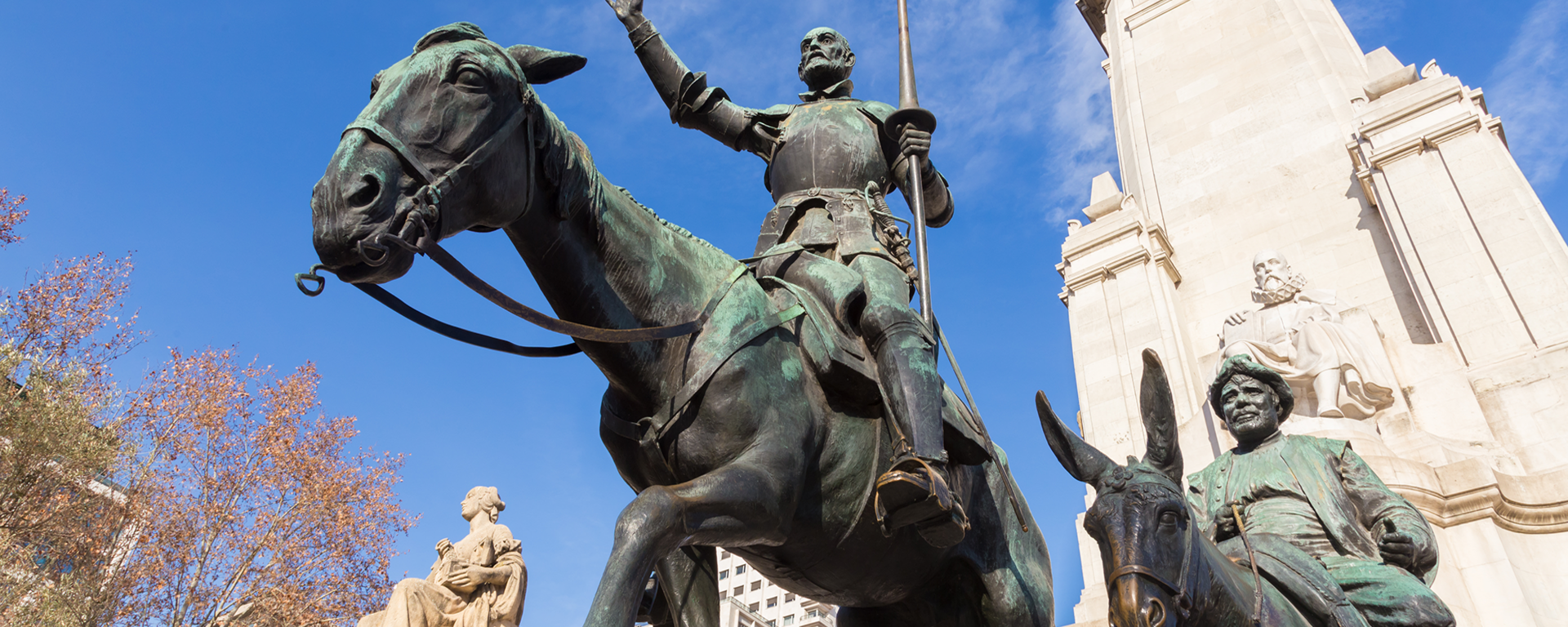 Stone statue of Miguel de Cervantes and bronze sculptures of Don Quixote and Sancho Panza on the Square of Spain (Plaza de Espana) in Madrid.