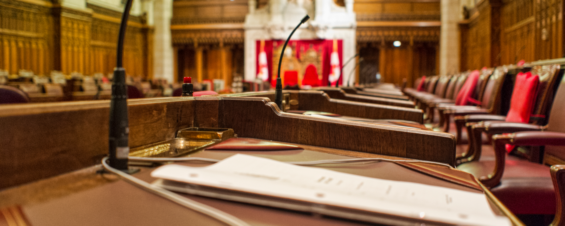 Close up of a Senator's desk with paperwork. Image taken in the chambers of the Senate of Canada, in the Parliament Buildings in Ottawa, Canada. The Speaker's chair can be seen in the background. A narrow depth off field has been applied to this image.