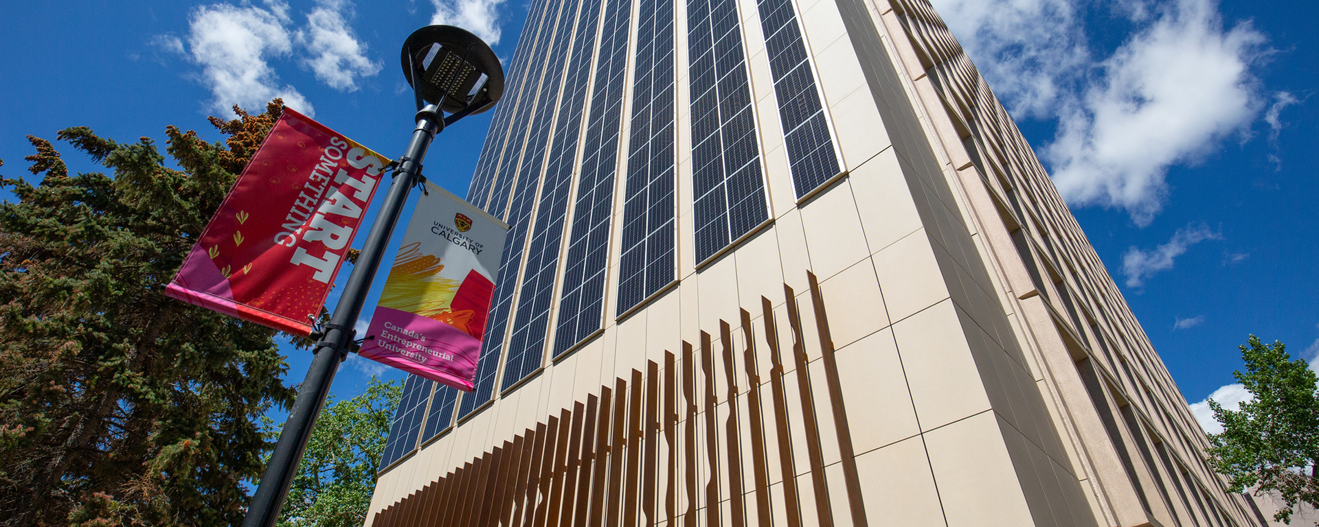 The Social Sciences building as seen from below looking up. It's a bright day. The UCalgary Start Something flag is visible in the frame.