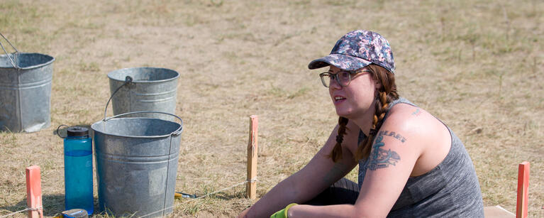A researcher sits in an archaeological excavation at Cluny Fortified Village