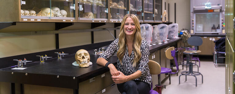 Adrianne Offenbecker sits in a lab amongst primate skulls