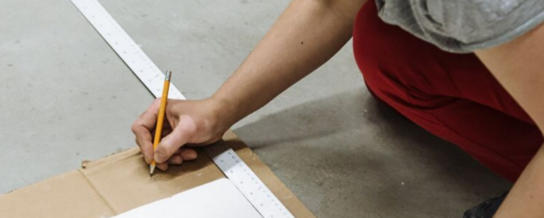 A student crouches on the floor to draft