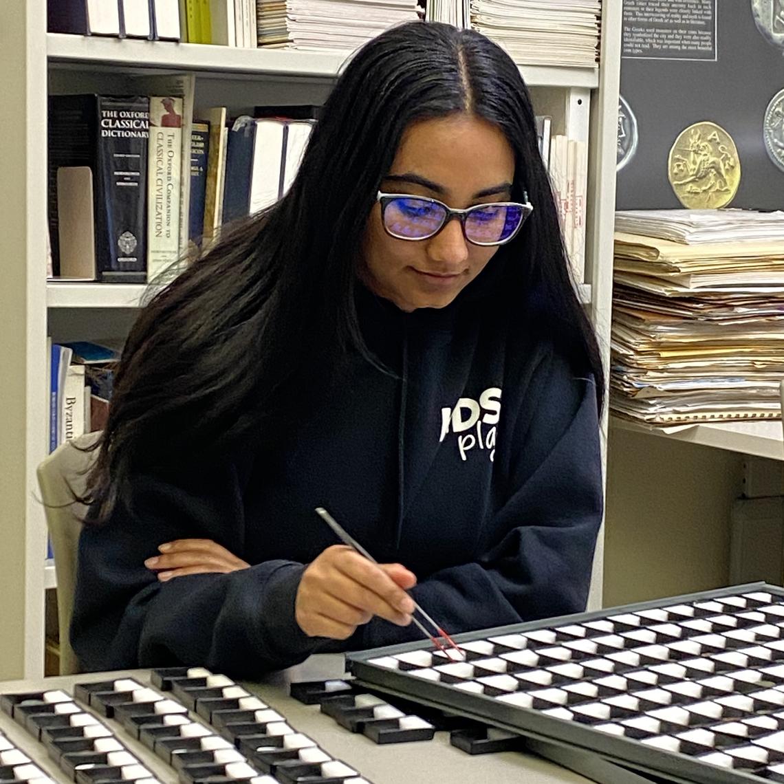 A female student of colour examines artifacts