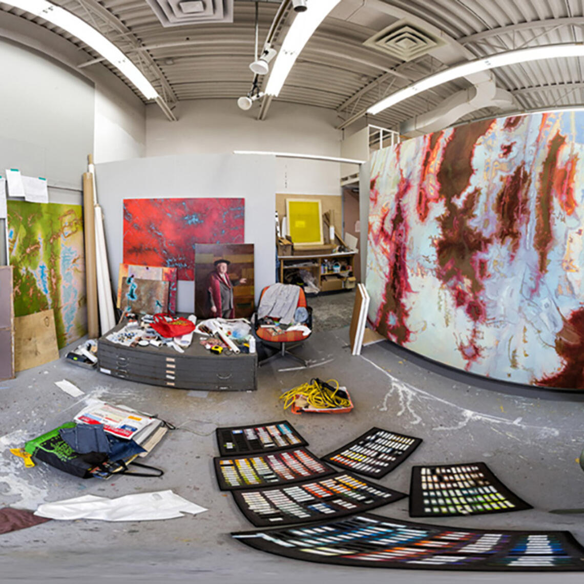 A fisheye view of an artist studio in the department, with canvases hanging on the wall and materials strewn about the space.