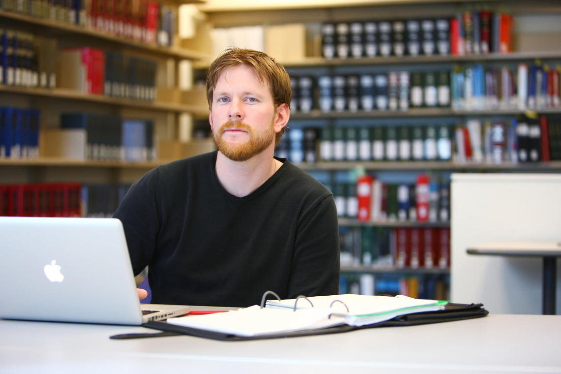 A student with a laptop and papers