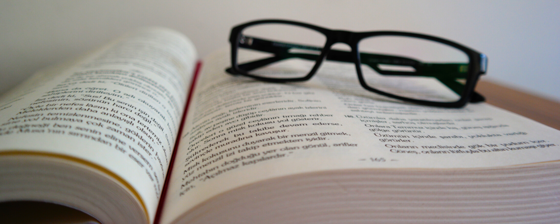Stock image of an open book with glasses on it