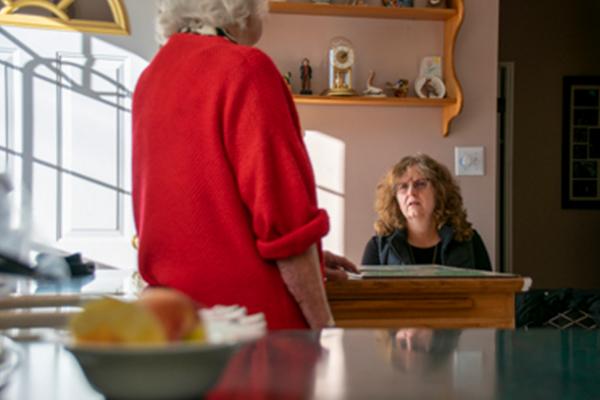 Hannah Henry photo of standing older white woman talking to seated middle aged white woman 