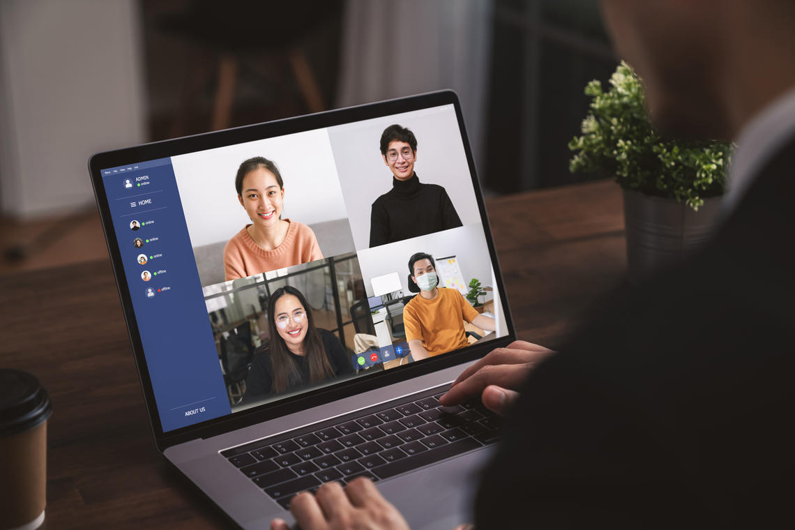 Stock image of a person in business dress in a video call on their laptop with four colleagues.