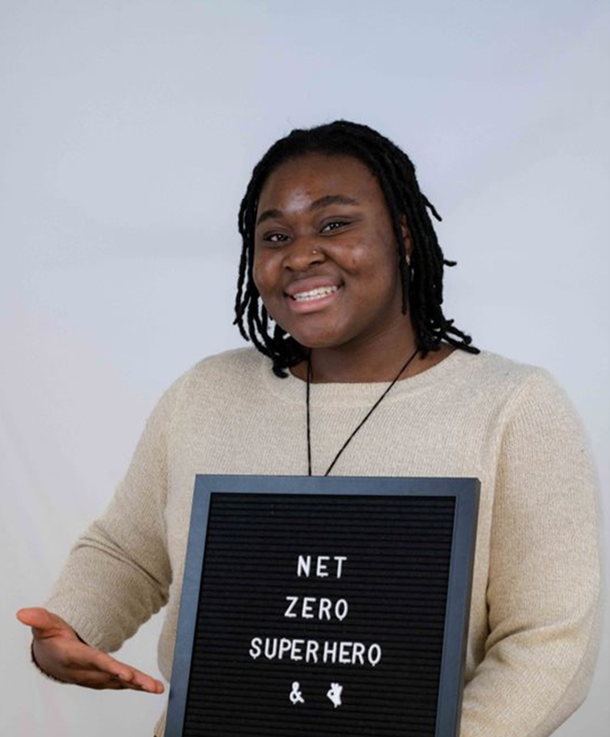 A co-op student displaying a sign saying "net-zero superhero"