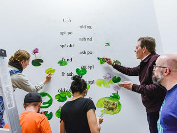 (l to r): Alumna Chelsea Rushton, alumnus Colin Martin, student Avril Lopez, Dean Richard Sigurdson, and alumnus derek bealieu work on the collaborative mural