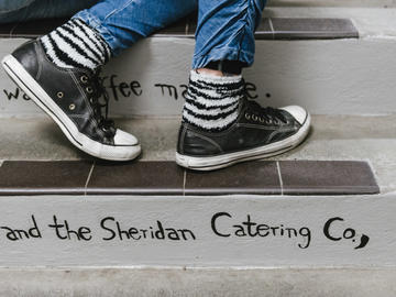 A pair of black leather Converse and striped socks stand on one of the steps 