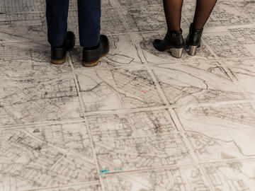 Two people wearing dress shoes stand on the map
